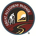 Round logo of silhouette riding a bike through a trail.