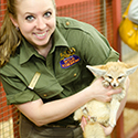 Zookeeper smiling, holding a fennec fox.