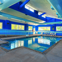 Shallow, blue indoor pool with windows.